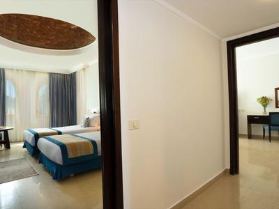 Corridoio con vista su una camera d'albergo con letto, finestra e mobili in toni caldi.