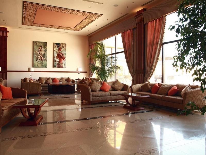 Großes Wohnzimmer mit Sofas, Kissen, Vorhängen, Pflanzen und Marmorfußboden in warmem Licht.