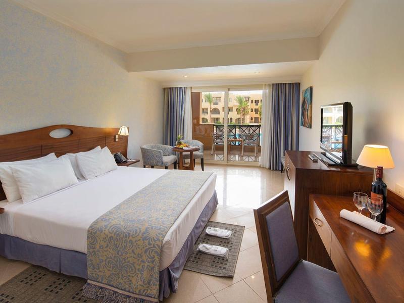 Modernes Hotelzimmer mit Doppelbett, Schreibtisch, TV und einem Balkon mit Ausblick.