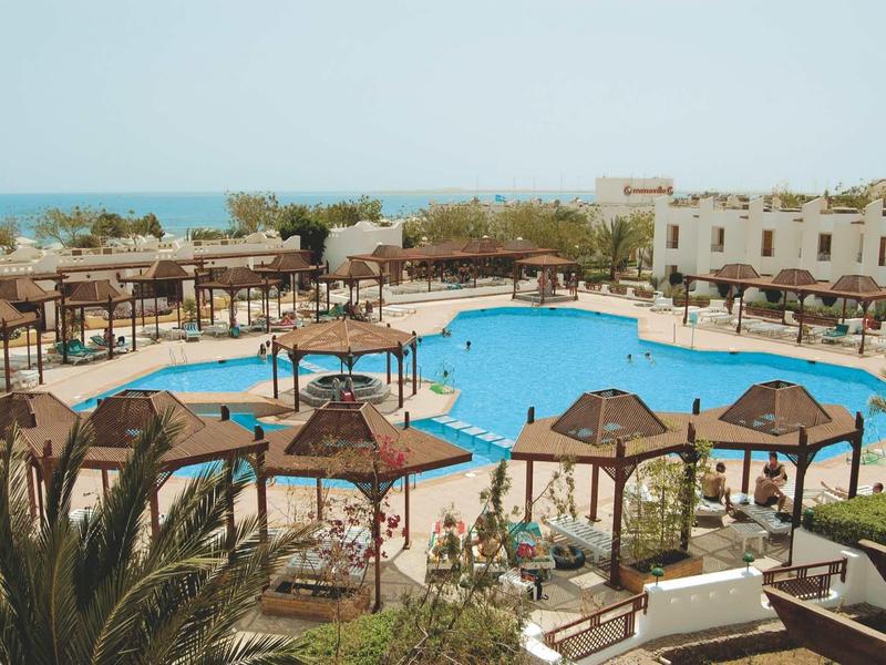 Grande piscine avec parasols et chaises longues dans une station balnéaire au bord de la mer.