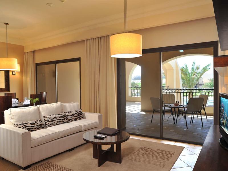 Cozy living room with white sofa, coffee table, and sliding doors opening to a balcony with table and chairs.