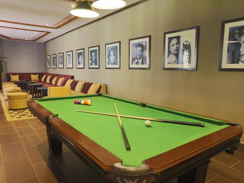 Room with pool table, wooden furniture, and framed black-and-white photos on the wall.