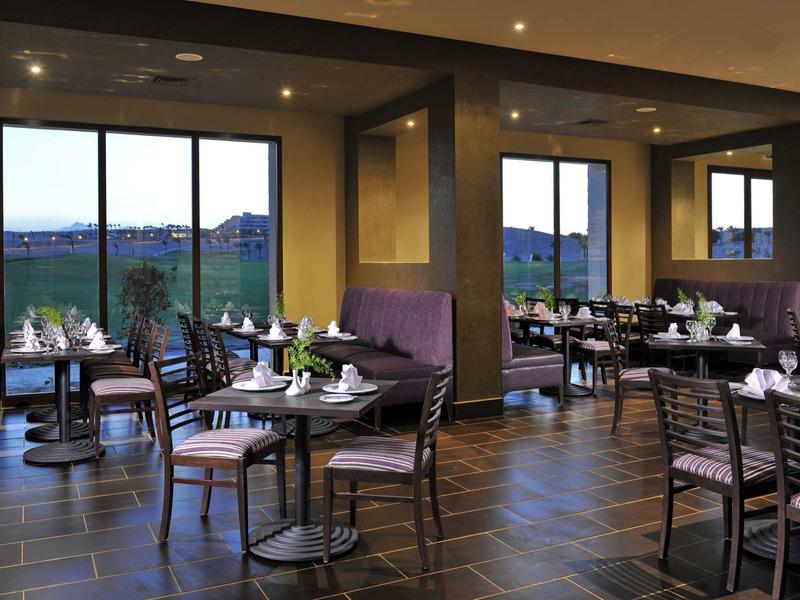 Cozy hotel dining area with tables, chairs, and large windows showing a scenic view.