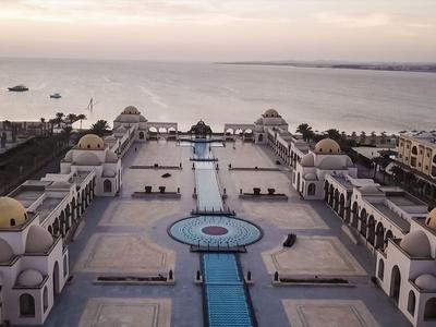 Vista aerea di un hotel di lusso con piscina e vista mare al tramonto.