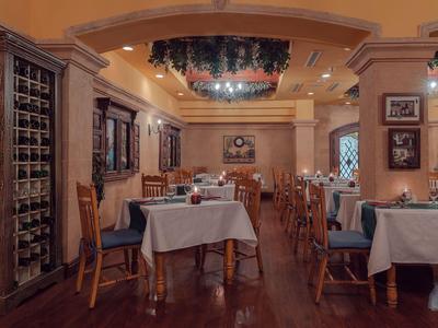 Ristorante elegante con tavoli apparecchiati, pavimento in legno e illuminazione calda.