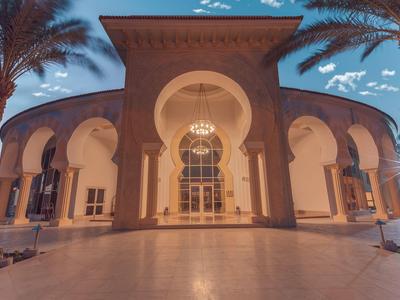 Edificio elegante con archi e palme al crepuscolo sotto un cielo blu.