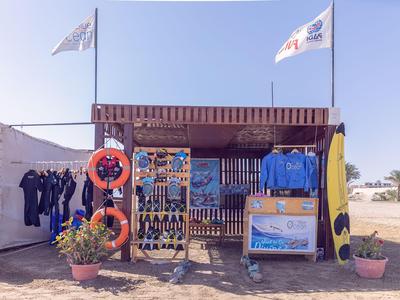 Negozio subacqueo all'aperto con attrezzatura subacquea, mute e due bandiere sotto un cielo limpido