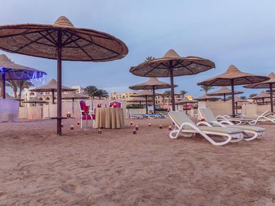 Spiaggia con lettini bianchi e ombrelloni di paglia sotto un cielo nuvoloso.