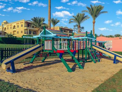 Area giochi colorata con scivoli e altalene in un giardino soleggiato dell'hotel.