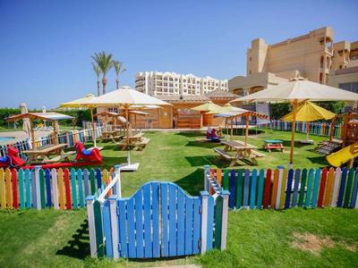 Outdoor kids' play area with slides and colorful fencing at a sunny resort garden.