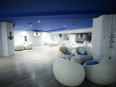 Spacious lounge area with white woven chairs and blue cushions under a blue ceiling.