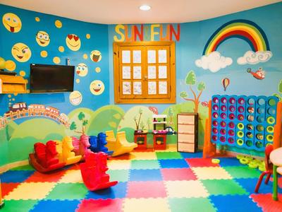 Colorful kids' playroom with emoji wall, foam floor tiles, toys, and a rainbow decoration.