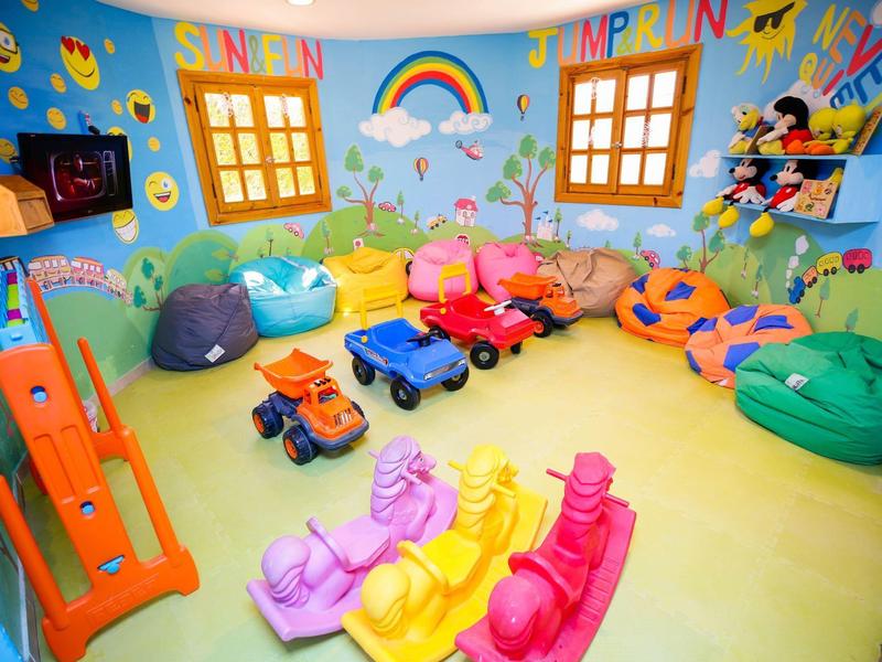 Colorful children's playroom with toys, bean bags, slide, and wall decorations.
