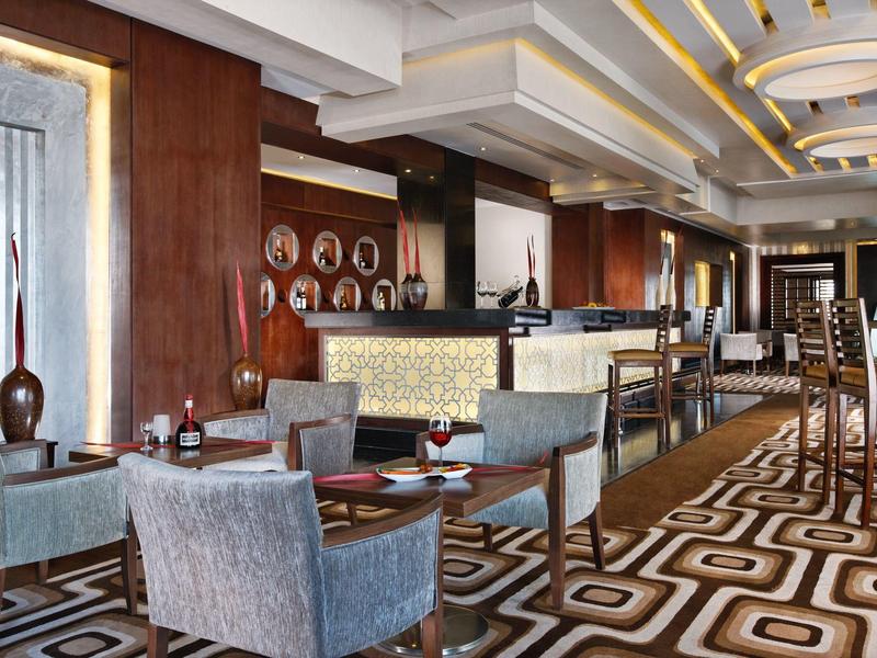 Eleganter Barbereich mit modernen Sesseln, geometrischem Teppich und warmen Holzwänden.