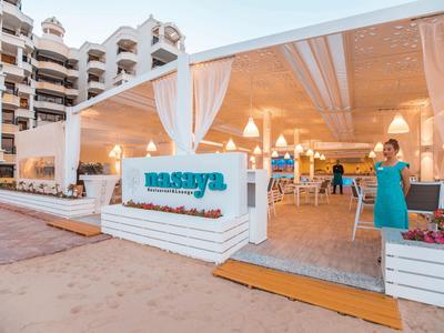 Zewnętrzny obszar oświetlonej restauracji na plaży z tarasem i miejscami do siedzenia o zmierzchu.