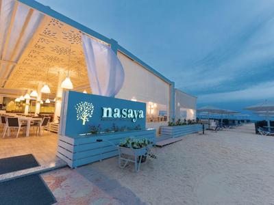 Nowoczesny klub plażowy z podświetlonym logo i miejscami do siedzenia o zmierzchu.