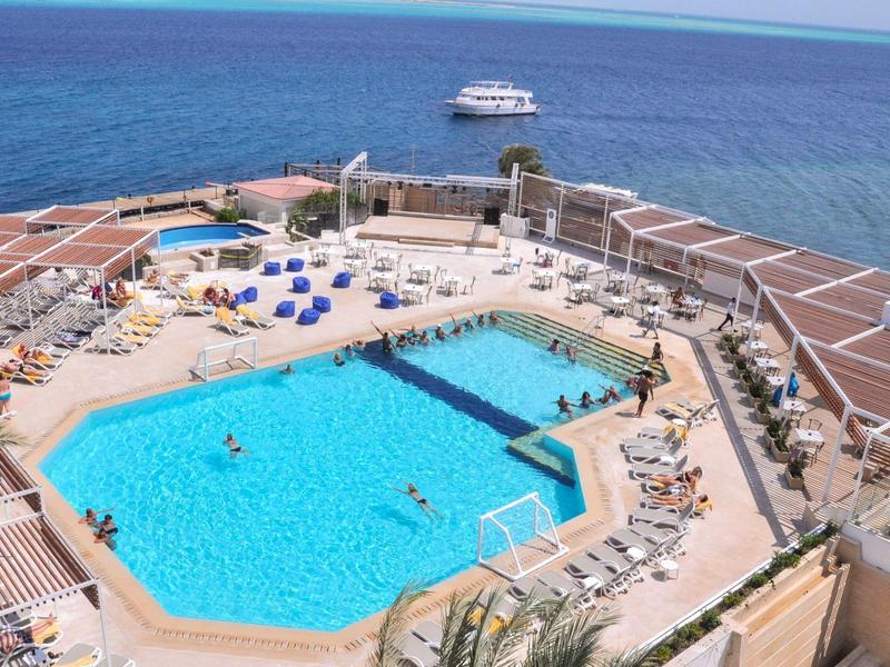 Großes Sechseck-Schwimmbecken mit Liegestühlen und Meerblick im Hotel.