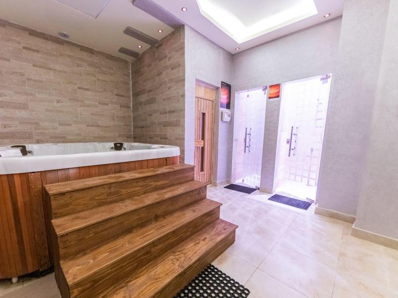 Moderner Whirlpool mit Holzverkleidung und Treppe in einem hellen Wellnessbereich.