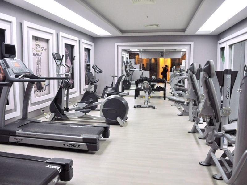 Moderner Fitnessraum mit Laufbändern, Ergometern und Gewichten in einem Hotel.
