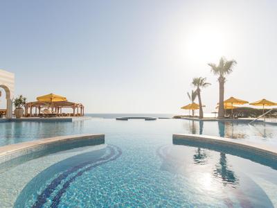 Infinity-Pool mit Blick auf das Meer unter klarem Himmel und Sonnenschirmen