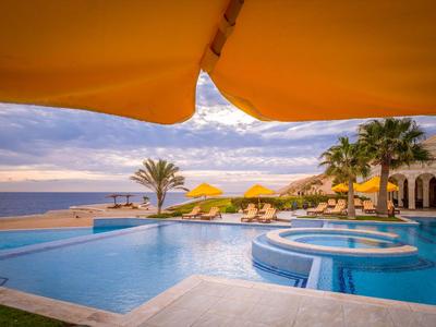 Infinity-Pool mit Sonnenschirmen und Blick auf das Meer bei Sonnenuntergang.
