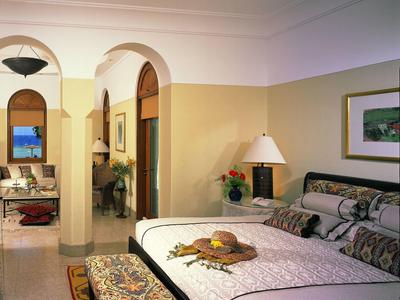 Hotel room with elegant furniture, large bed, archways, and a lamp on the bedside table.