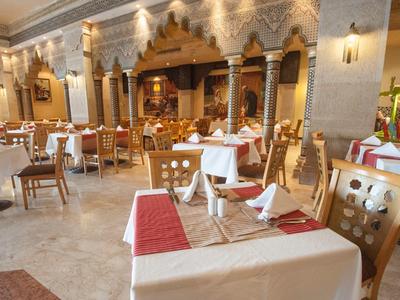 Elegantes Restaurant mit gedeckten Tischen, Holzstühlen und dekorativen Säulen an der Wand.