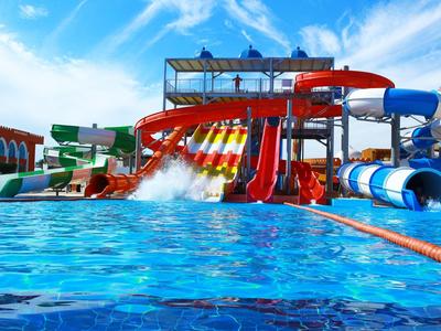 Buntes Wasserrutschenparadies mit mehreren Rutschen und großem Becken unter blauem Himmel.