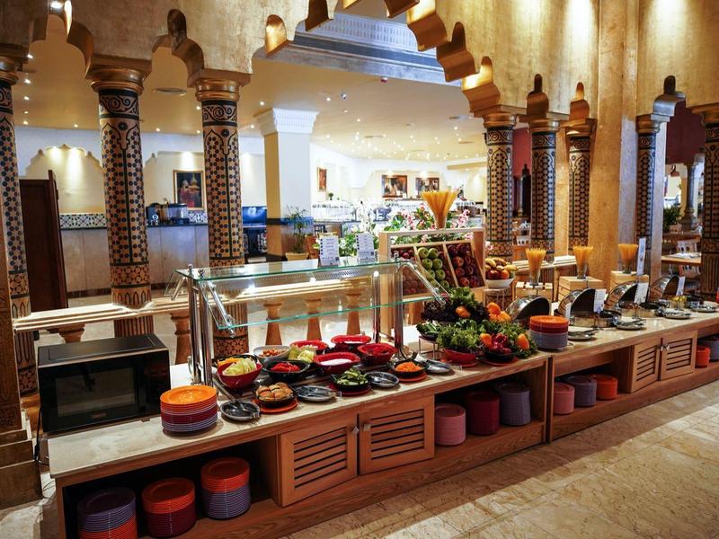 Buffet mit bunten Tellern, Schalen und frischem Gemüse in warm beleuchtetem, traditionellem Raum.