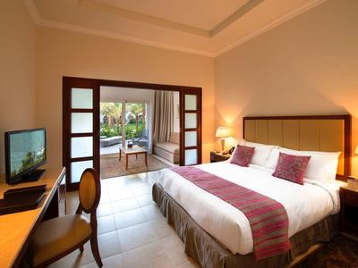 Gemütliches Schlafzimmer mit großem Bett, Schreibtisch, TV und Zugang zur Terrasse mit Gartenblick.