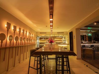 Modernes Restaurant mit Holztischen, Hockern und dekorativen Holzlöffeln an der Wand.