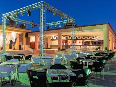 Illuminated outdoor area with tables and chairs in front of a restaurant at night.