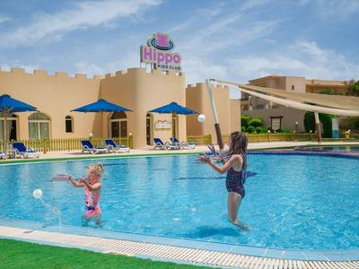 Children playing with nets at the blue pool in front of Hippo Hotel on a sunny day.