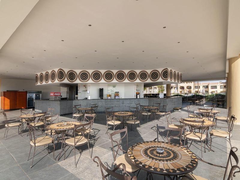 Modern hotel outdoor area with ornate metal tables and chairs under a covered space.