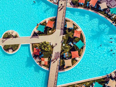 Von oben sichtbarer Pool mit Brücke und Sonnenschirmen in einem Hotelresort.
