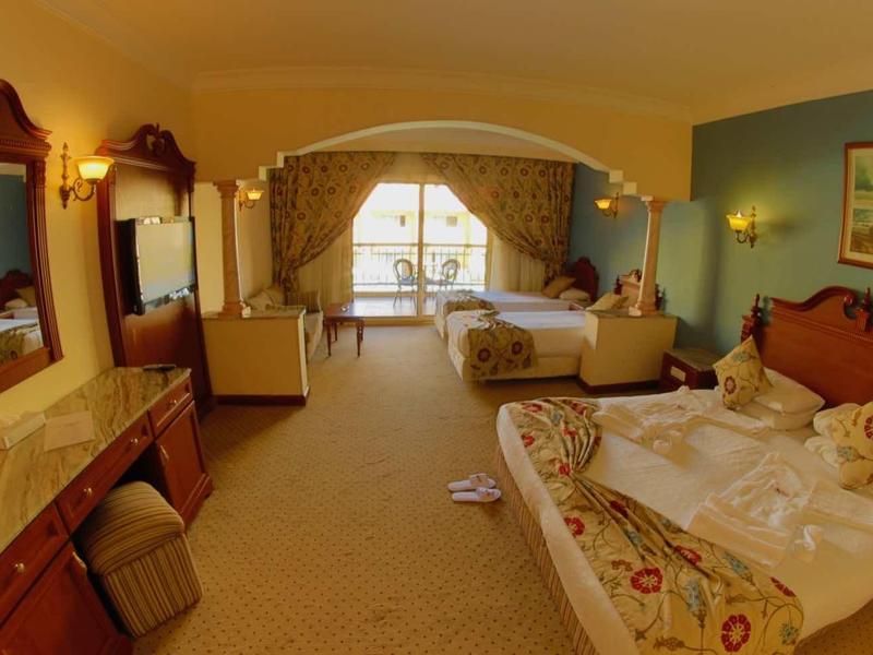 Grande chambre d'hôtel avec lit double, canapé, bureau et balcon avec vue sur la mer.