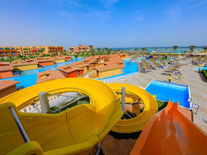 Vue sur les toboggans aquatiques et la piscine dans une station balnéaire ensoleillée avec ciel clair.