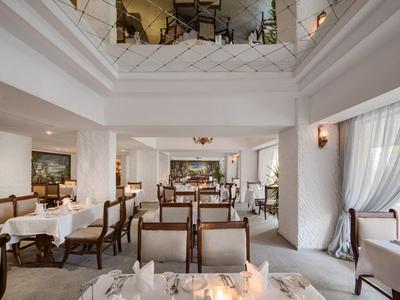 Restaurante iluminado con paredes blancas, mesas preparadas y sillas de madera marrón en un hotel.