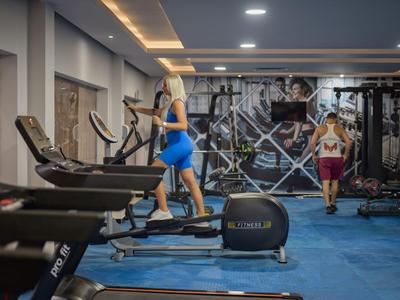 Fitnessruimte met loopbanden en twee mensen die sporten.