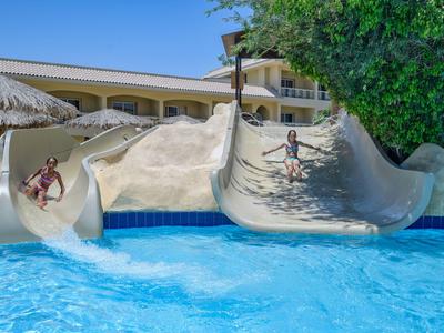 Twee glijbanen met kinderen die in een zwembad bij een hotelresort glijden.