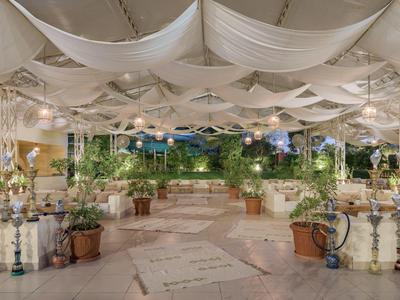 Heldere open binnenplaats met tapijt, planten en talrijke waterpijpen aan beide zijden.