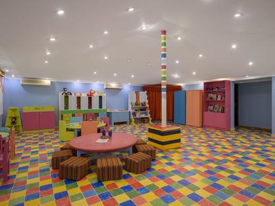 Sala de juegos colorida y amigable para niños con suelo multicolor y mesa redonda con cojines.