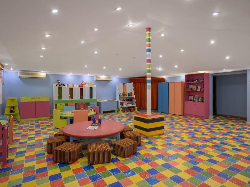 Sala de juegos colorida y amigable para niños con suelo multicolor y mesa redonda con cojines.