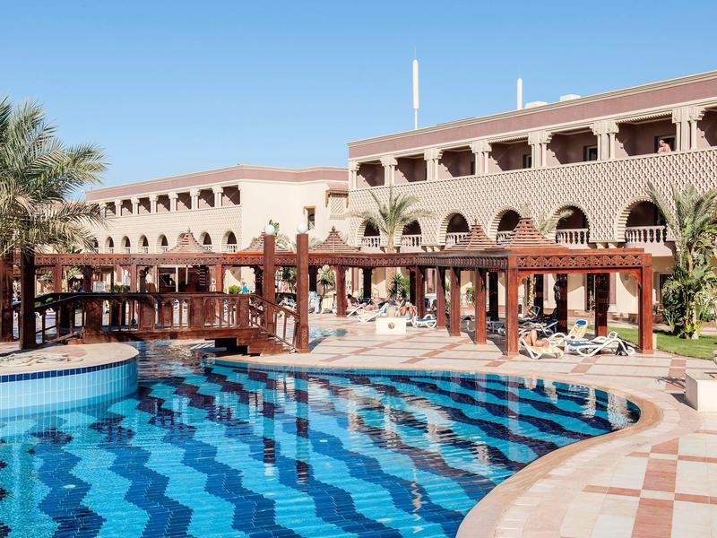 Luxusní hotelový bazén s palmami a sluneční terasou v teplém klimatu.