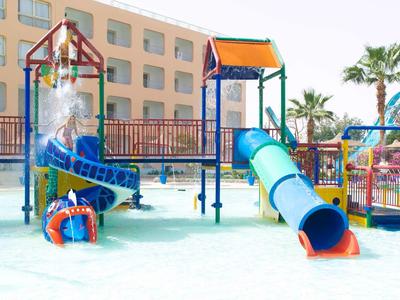 Bunter Wasserspielplatz mit Rutschen, Türmen und Wasserspritzern vor einem Hotelgebäude.