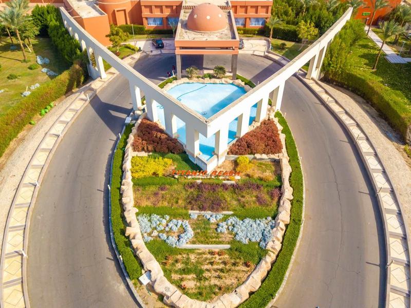 Letecký pohled na kruhový objezd s centrálním vodním prvkem a viditelnou architektonickou strukturou.