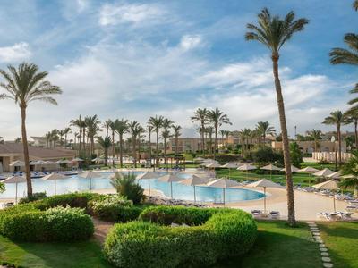 Gran piscina en un resort tropical con palmeras y sombrillas.