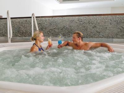 Pár relaxuje ve vířivce a připíjí si sklenicemi