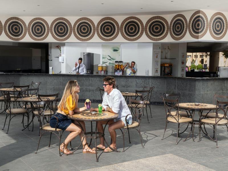 Pár sedí u stolu před moderním venkovním barem hotelu.