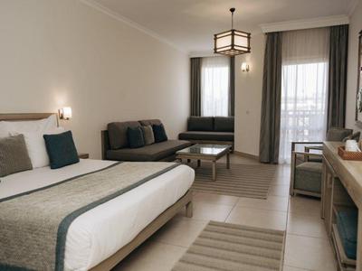 Modern eingerichtetes Hotelzimmer mit Doppelbett, Sofa, Schreibtisch und großem Fenster.